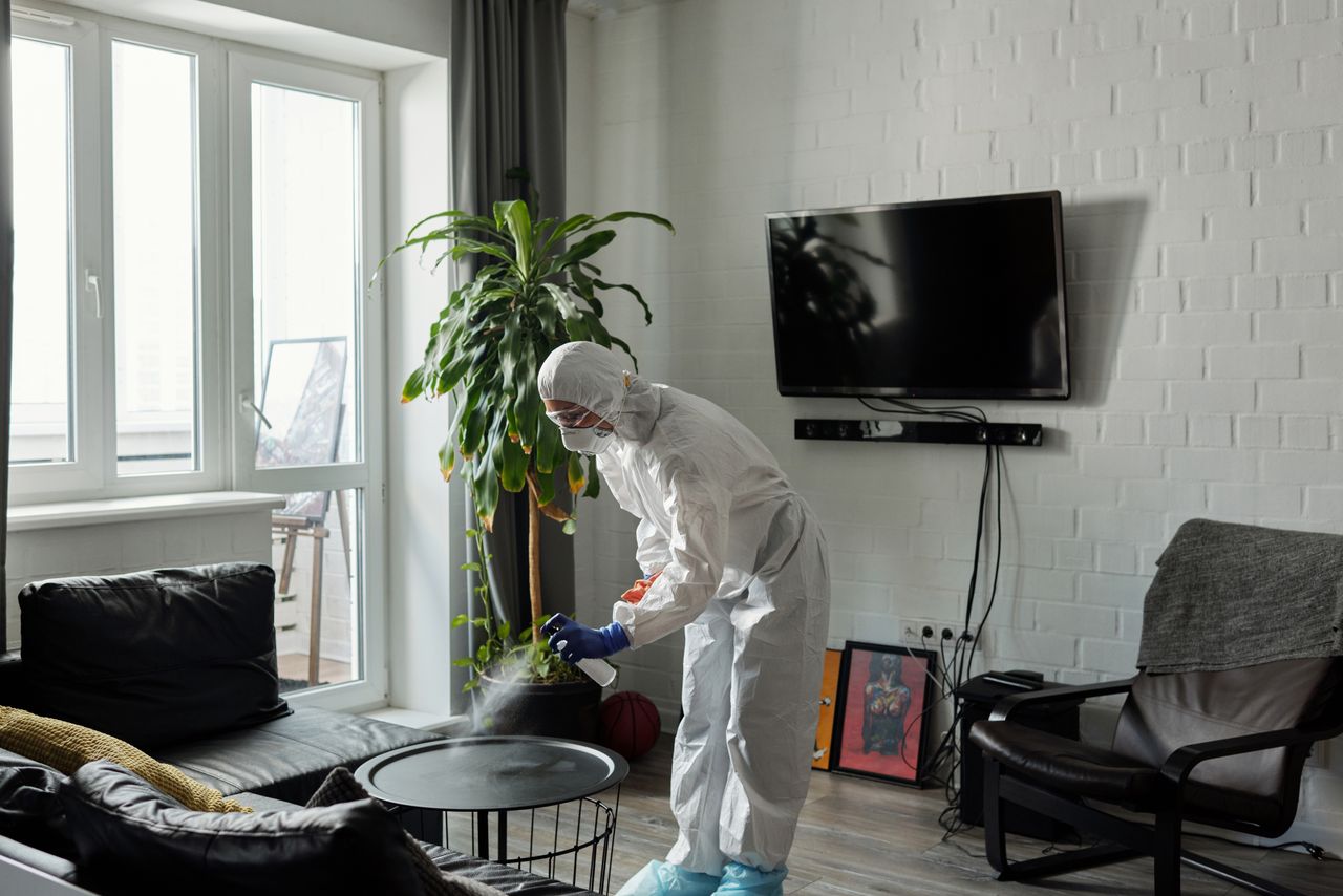 services-05 Worker in PPE disinfecting a living room, ensuring safety from viruses.
